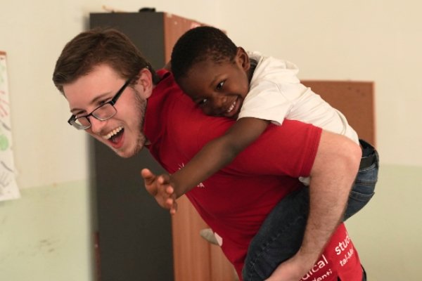 A child is on the back of a member of staff, they are having fun together