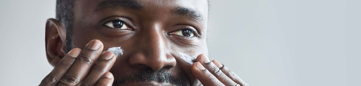 A man is putting cream into his cheeks