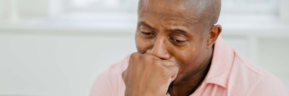 A man looking stressed and worried with his hand to his mouth